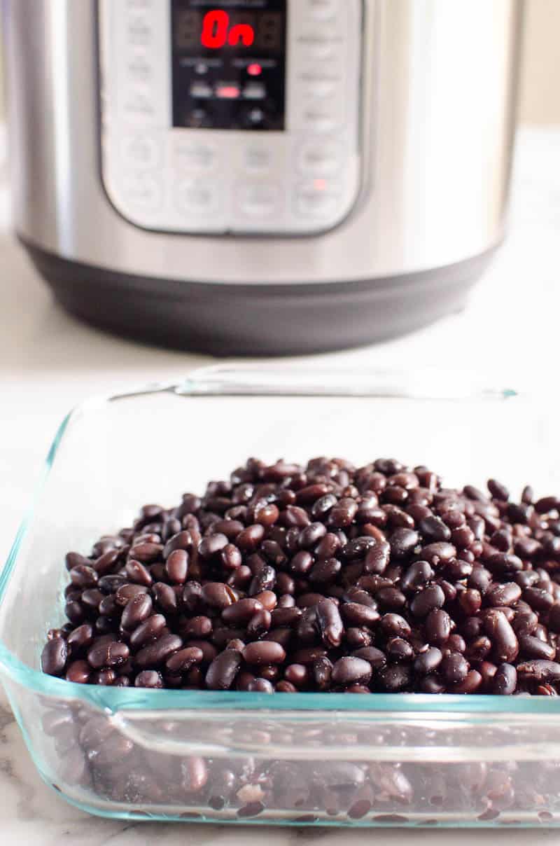 Instant pot black beans in glass dish and pressure cooker behind it.