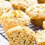 Healthy lemon zucchini muffins on baking rack with one muffin split open.
