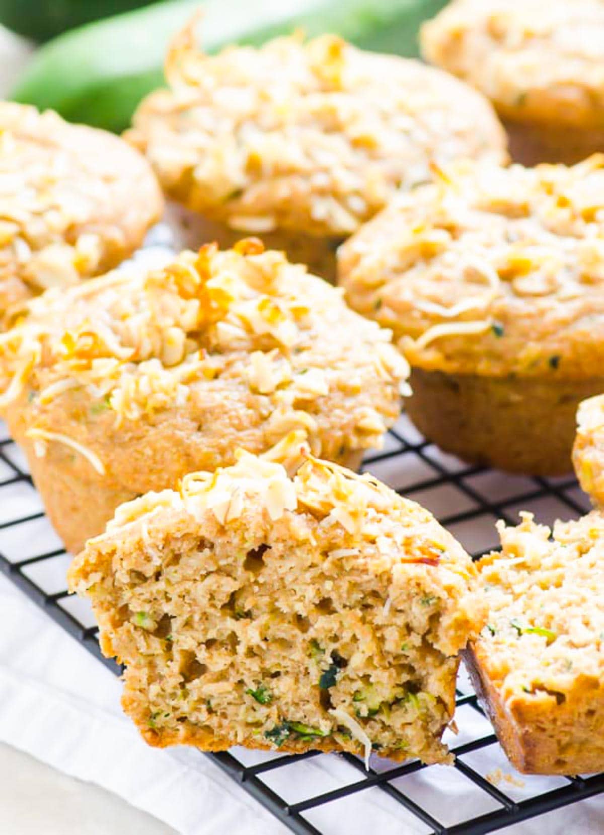 Healthy lemon zucchini muffins on baking rack with one muffin split open.