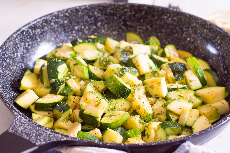 Sauteed zucchini garnished with fresh dill and served in black skillet.