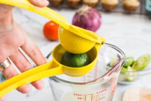 squeezing juice from lime with a lime squeezer over a bowl