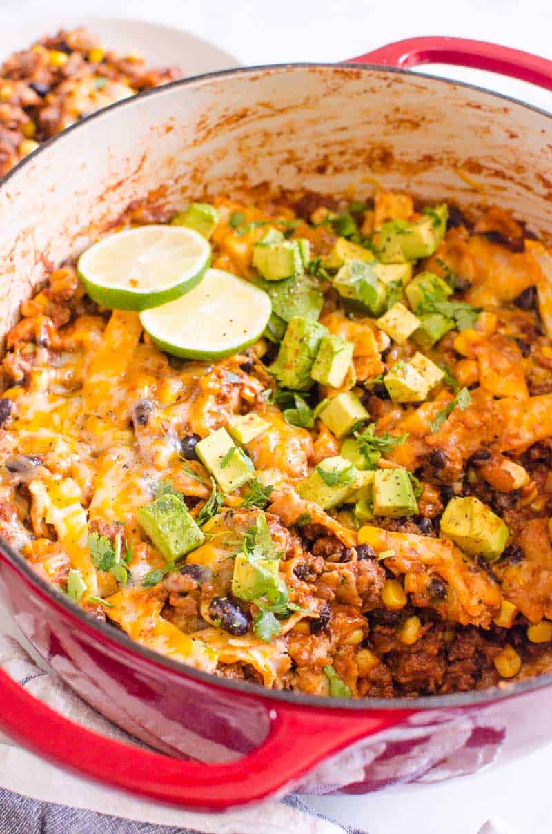 skillet enchiladas in a pot with avocado and lime slices