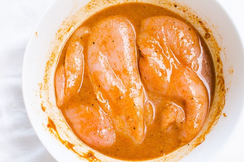 Chicken breasts marinating in chili lime chicken marinade in a bowl.