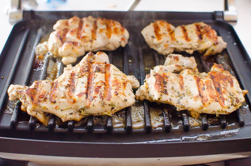 Marinated chicken grilling on indoor grill.