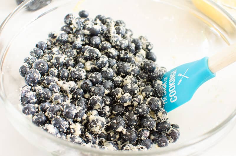 Blueberries coated with almond flour in a bowl with spatula.