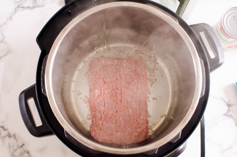 Meat inside Instant Pot sauteing.