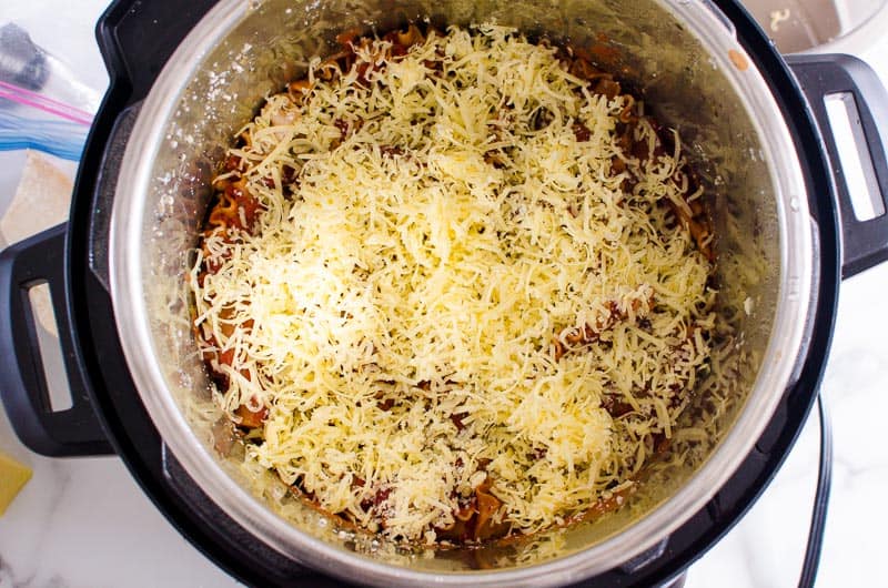 Cheese over lasagna ingredients in Instant Pot.