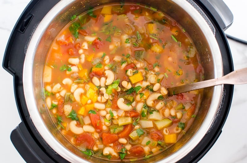 cooked minestrone in a pressure cooker with ladle