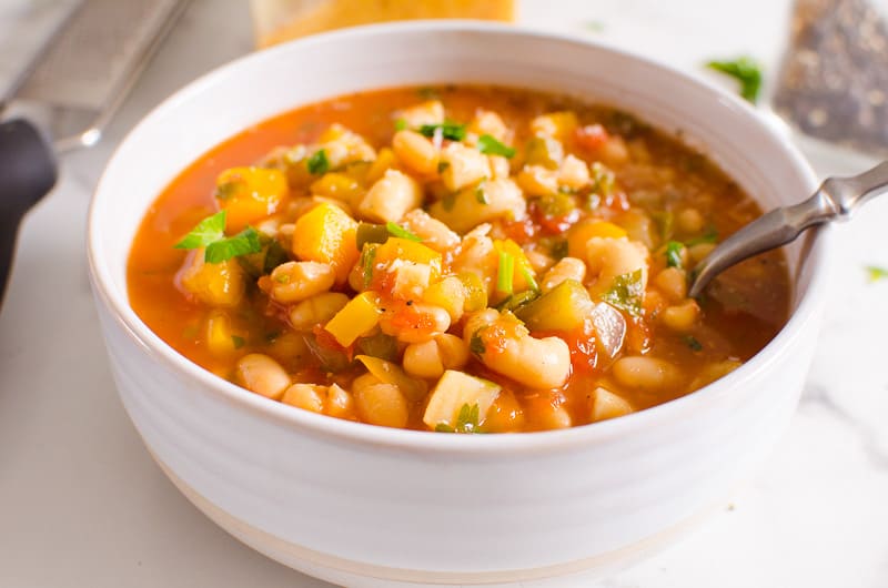 Instant pot minestrone garnished with parsley served in white bowl.