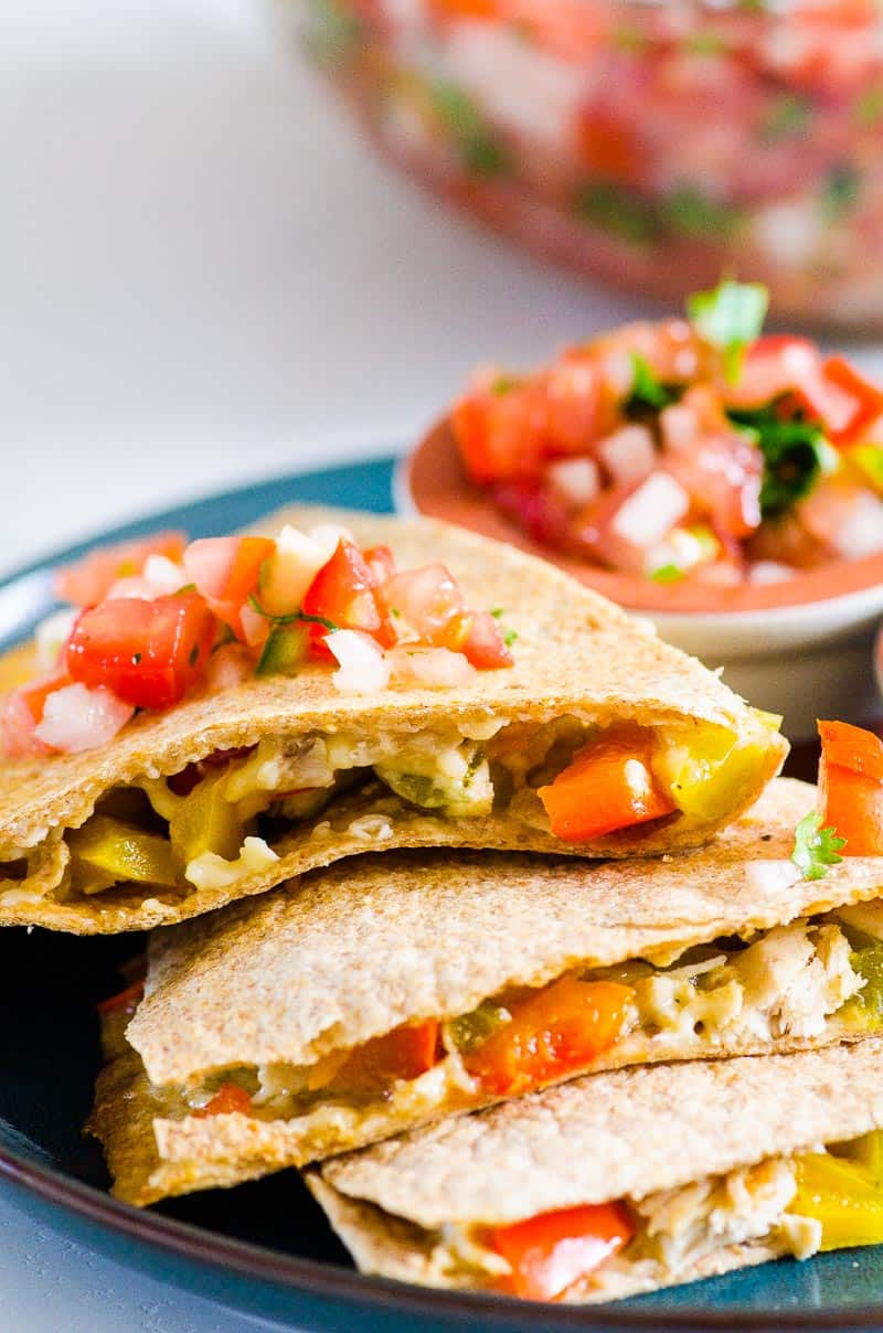 Chicken quesadilla stacked and topped with salsa on a plate.