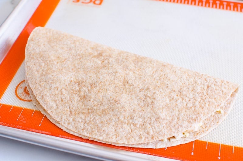 Folded tortilla on silpat lined baking sheet.
