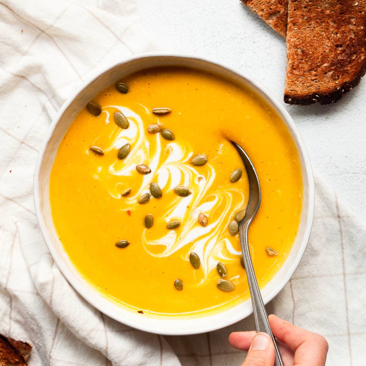 Healthy butternut squash soup in a bowl with spoon and bread toasts.