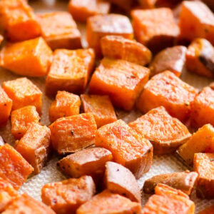 Healthy oven roasted sweet potatoes on silicone lined baking sheet.