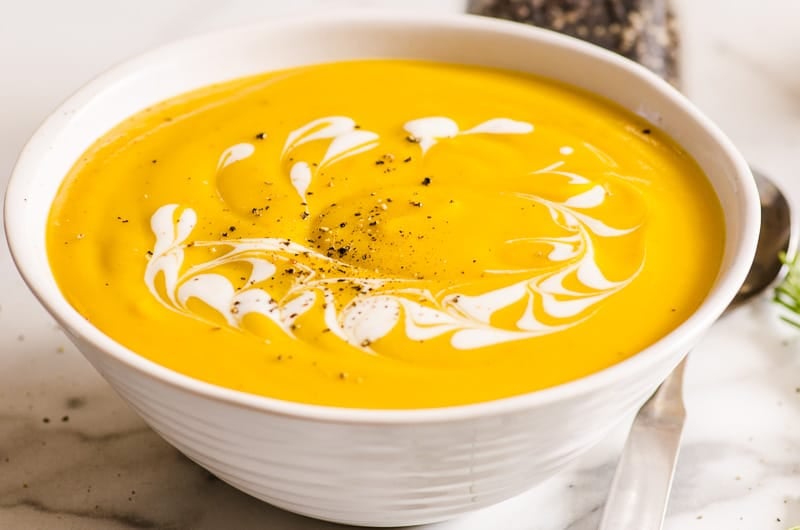 healthy butternut squash soup in a white bowl with cream