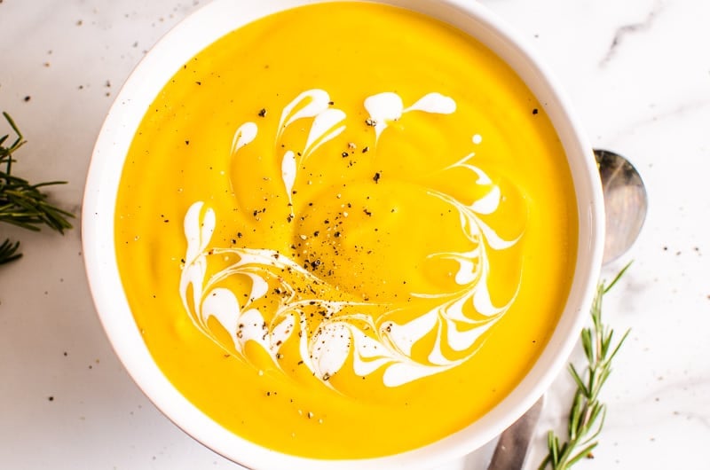 bowl of butternut squash soup garnished with pepper and cream