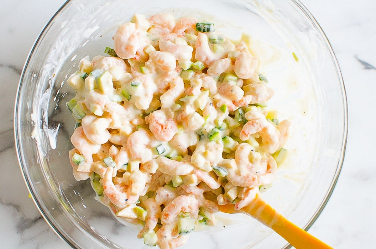 Healthy shrimp salad in bowl with yellow spatula.
