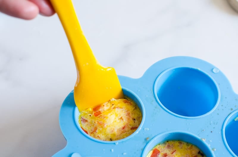 Removing egg bite from mold with spatula.