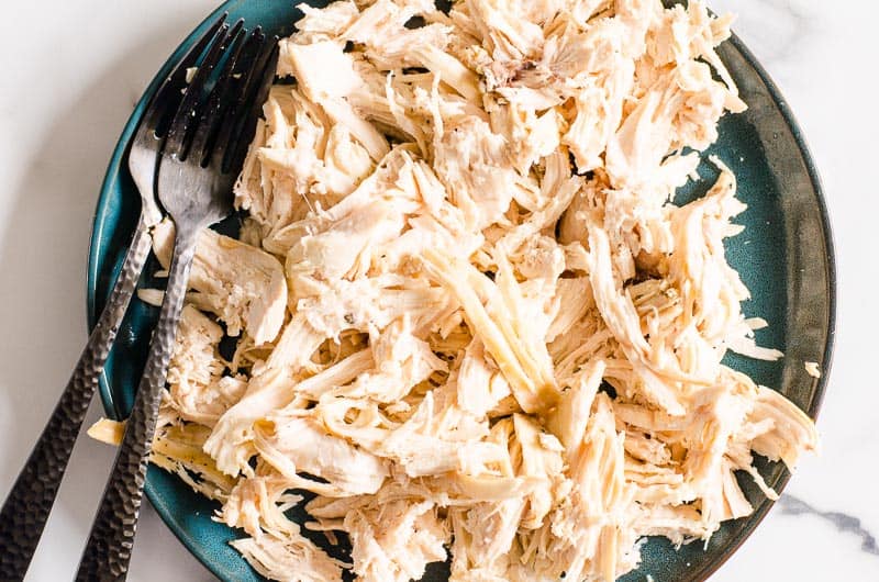 Instant Pot shredded chicken on a plate with two forks.