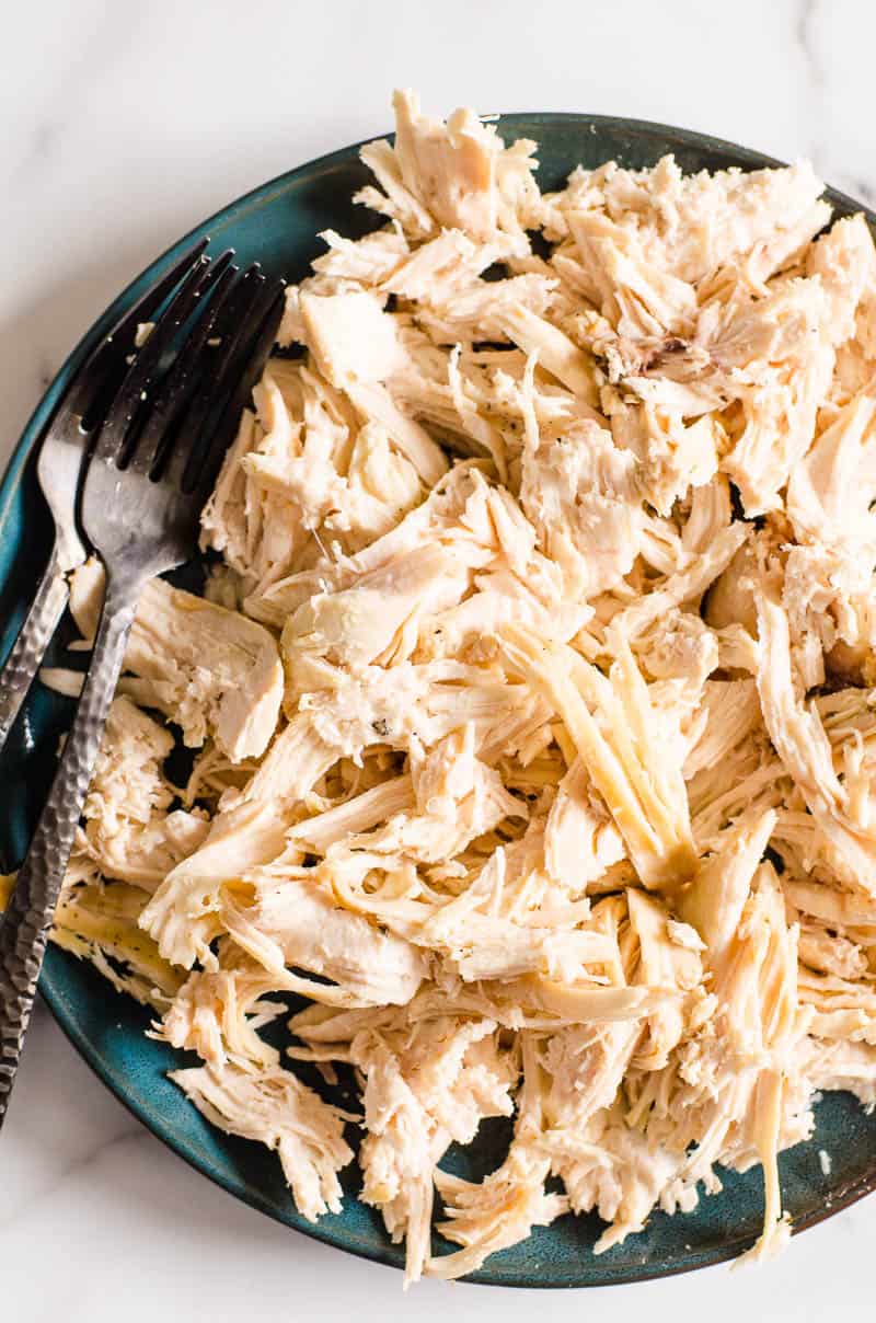Instant Pot shredded chicken on a plate with two forks.