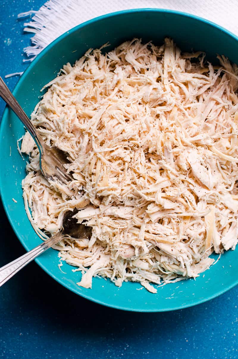 Instant Pot shredded chicken in a blue bowl with two forks.