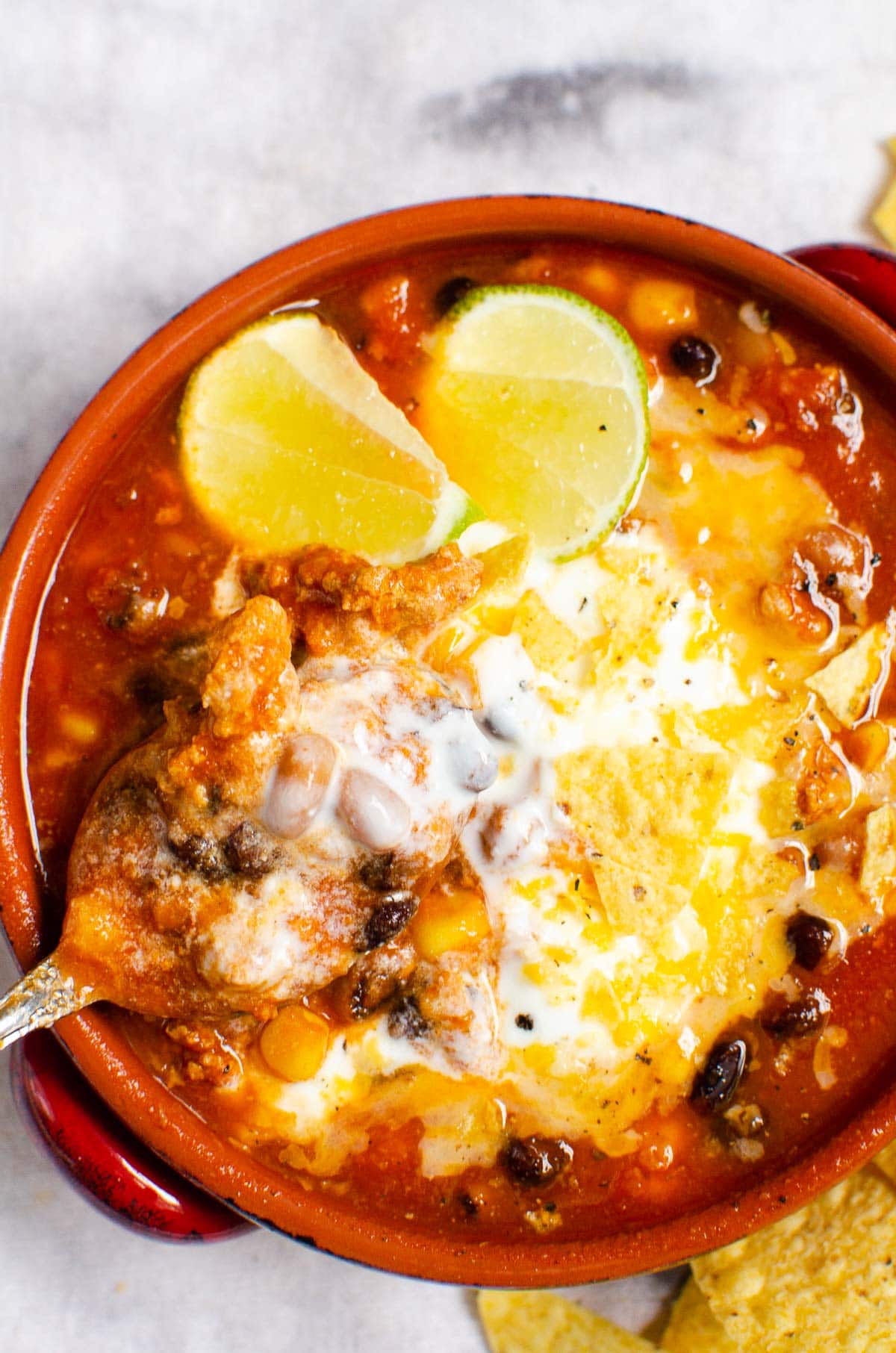 Instant Pot taco soup in a bowl with crushed chips, cheese and lime. 