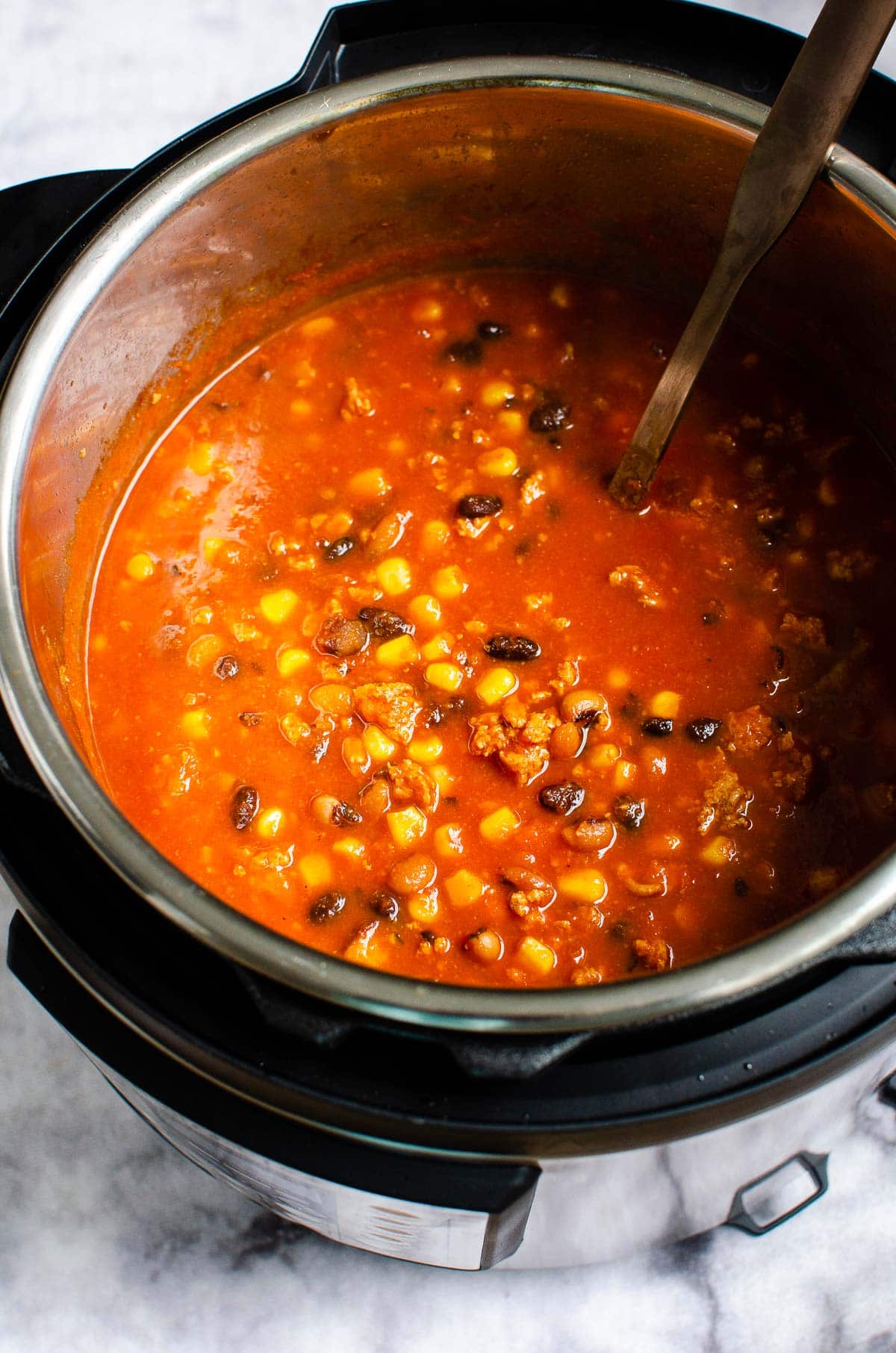 Instant pot taco soup with beans, corn and ground meat with soup ladle.