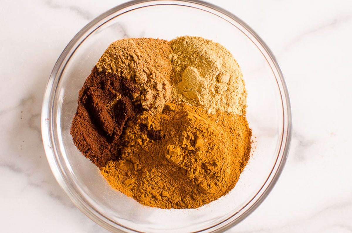 Cinnamon, nutmeg, ginger and cloves in glass bowl.