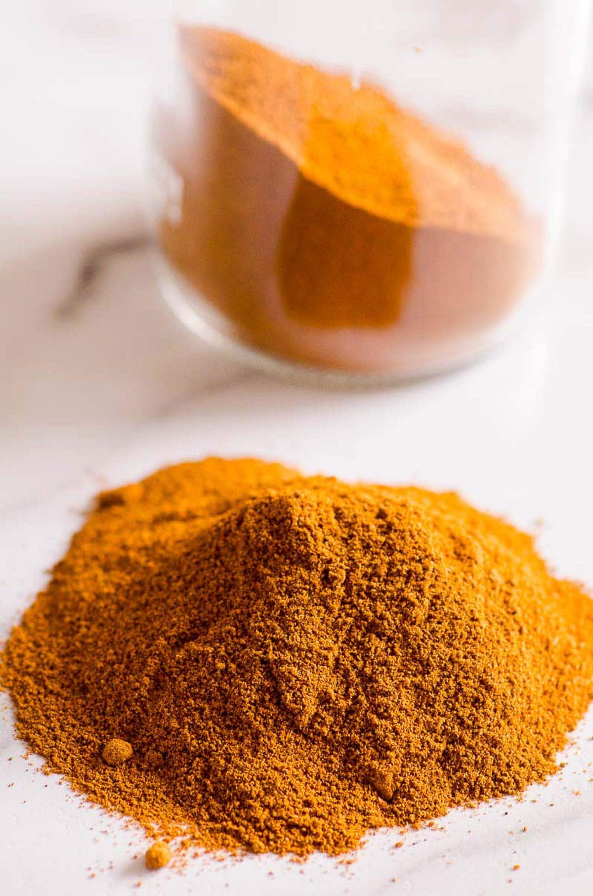 Homemade pumpkin pie spice substitute on countertop. Glass jar with spices.