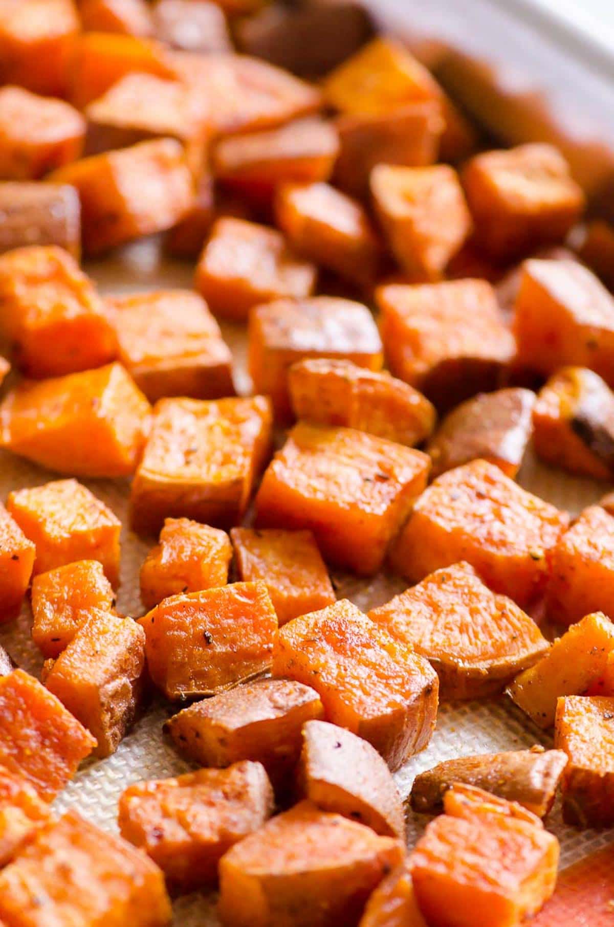 Healthy oven roasted sweet potatoes on silpat mat on baking sheet.