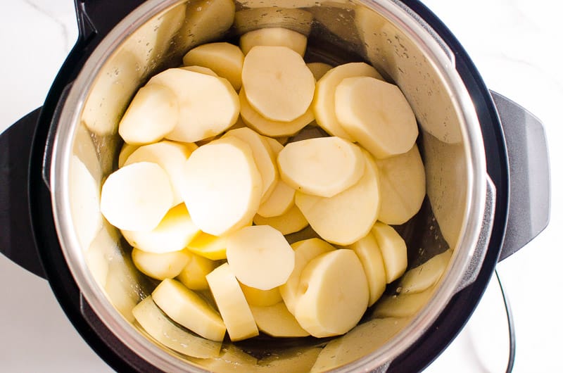 Peeled and sliced raw potatoes placed in instant pot.