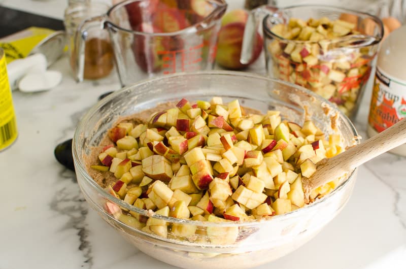 Diced apples added to quick bread batter in a bowl.