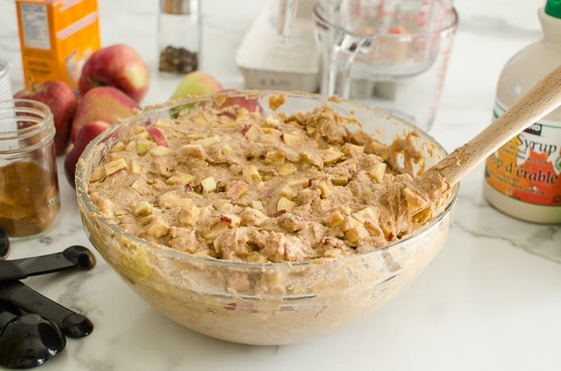 Diced apples being stirred into a bowl of bread batter.