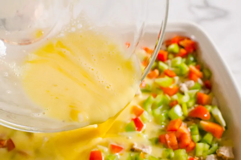 pouring egg mixture for breakfast casserole