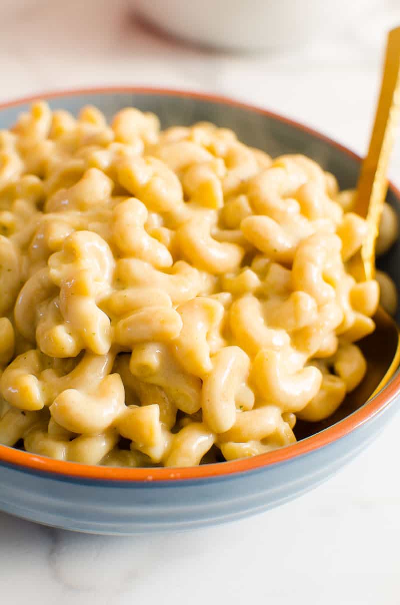 Healthy Mac and Cheese in a blue bowl with golden spoon.