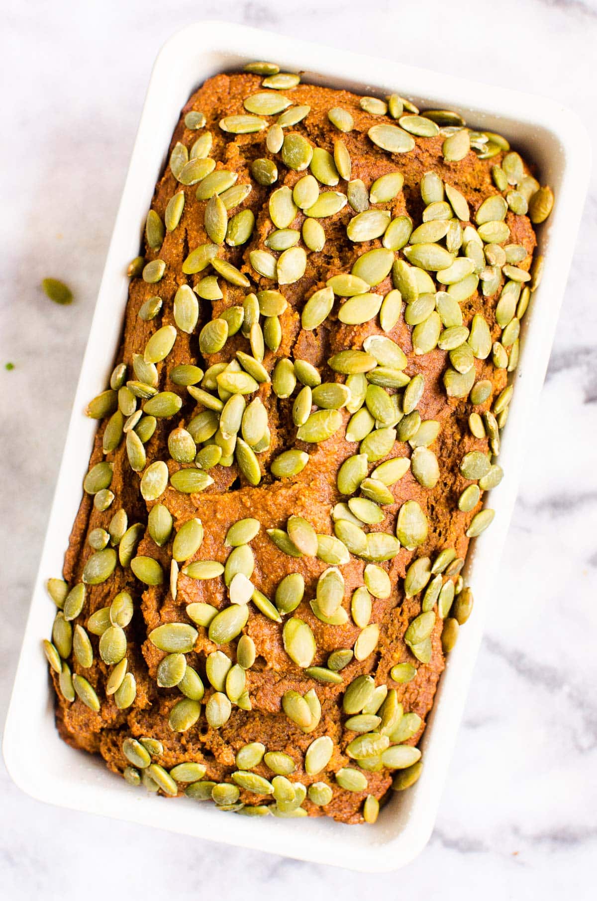 Healthy pumpkin bread studded with pepitas in a loaf pan.