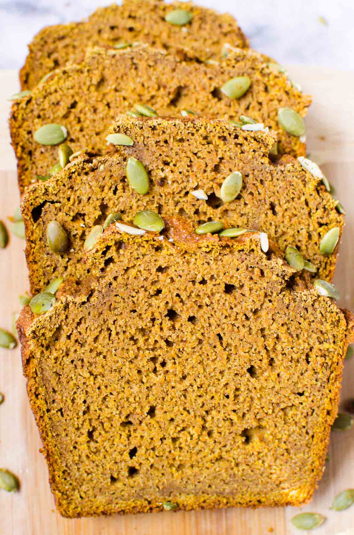 Four slices of healthy pumpkin bread on a cutting board.