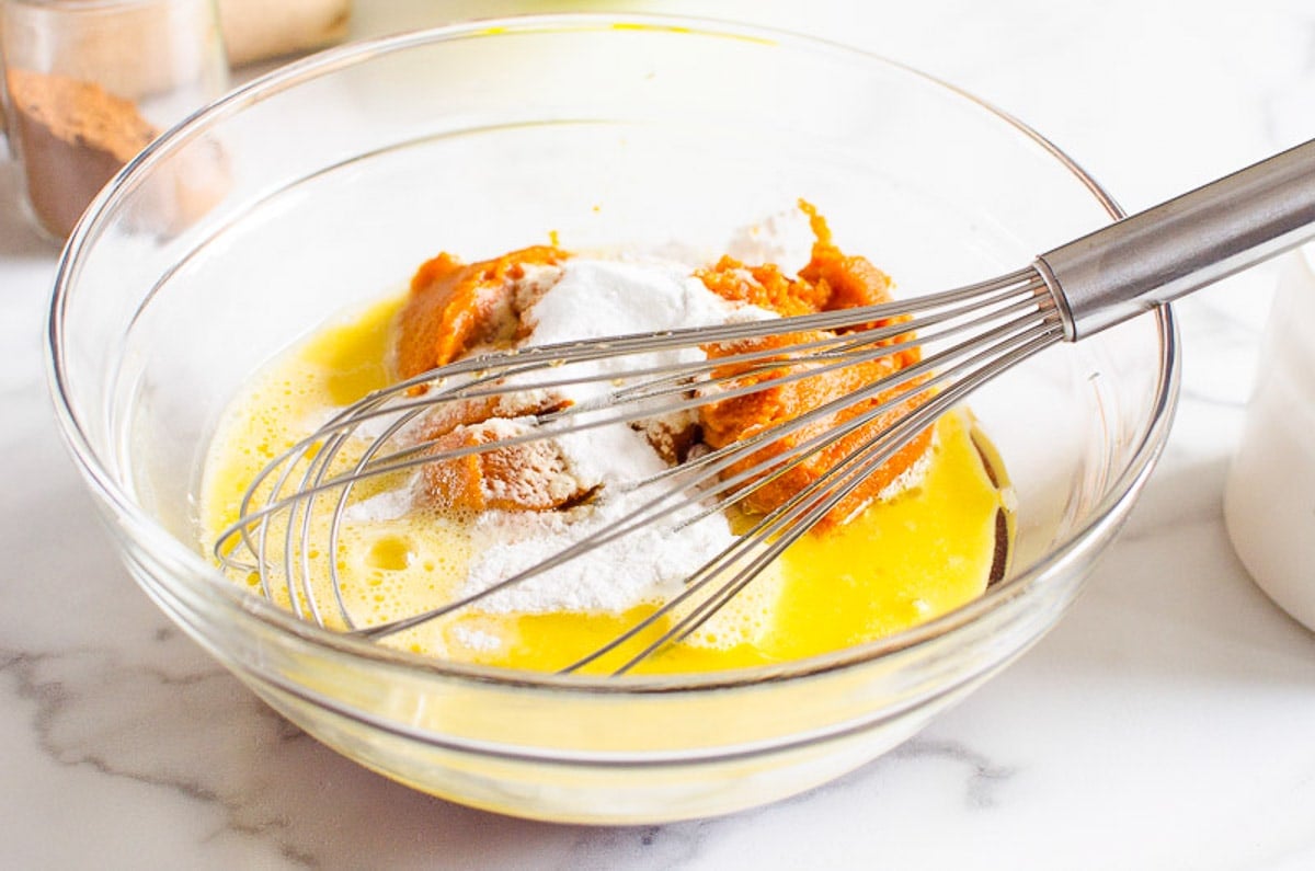 pumpkin, egg, maple syrup and baking staples being whisked in bowl.