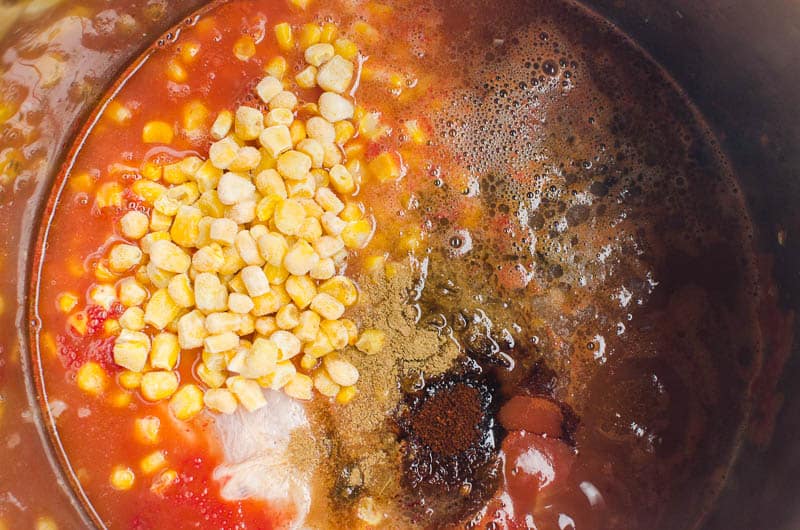 corn, tomato sauce, chicken breasts, spices in a pot