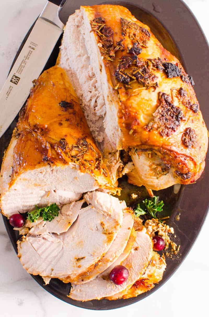Roast Turkey Breast on a platter with knife and fresh cranberries and garnish