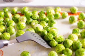 tossing brussels sprouts on a baking sheet