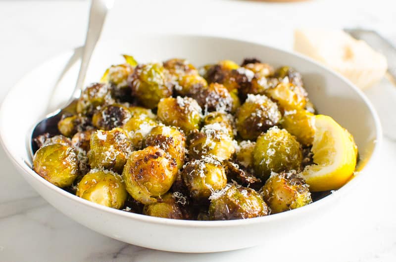 roasted brussels sprouts in white bowl garnished with parmesan