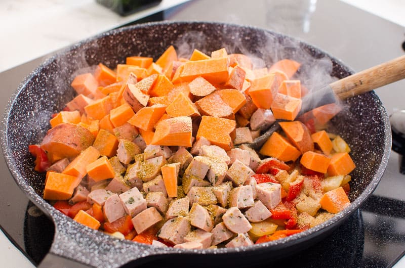 sauteing sweet potatoes, sausage, onion and peppers in skillet