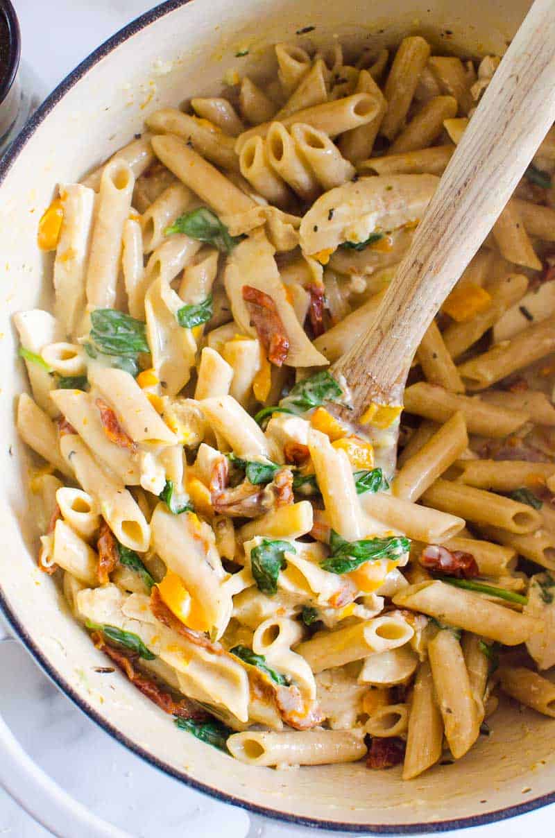 Healthy Tuscan Chicken Pasta in pot with serving spoon