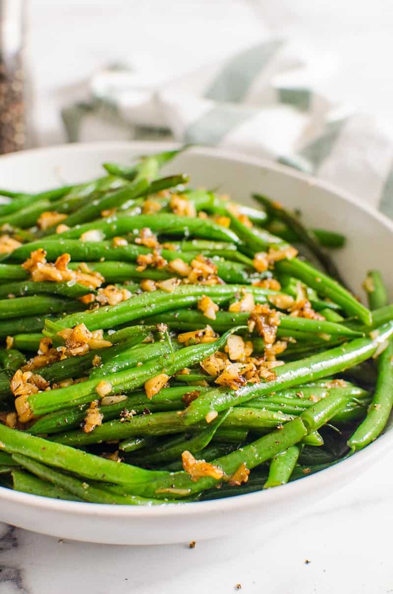 Garlic Green Beans in a bowl with garlic and linens in background