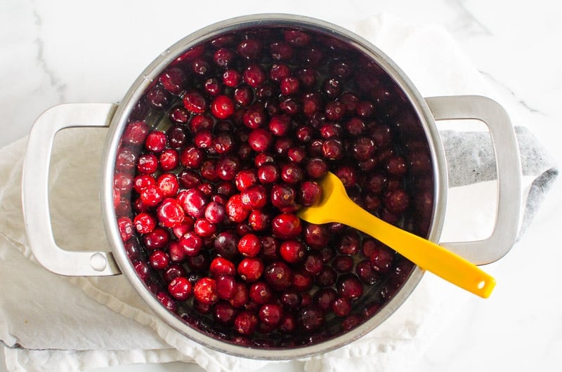 fresh cranberries, maple syrup and orange zest in a pot with spatula