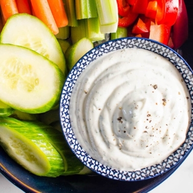 Healthy veggie dip in a bowl with fresh vegetables on platter.