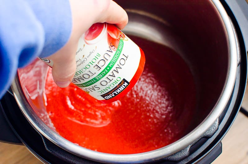 Adding a can of tomato sauce to Instant Pot.