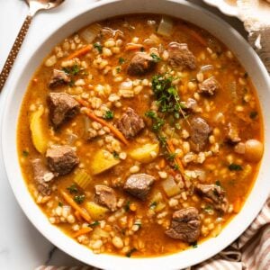 Beef barley soup garnished with thyme in a bowl.