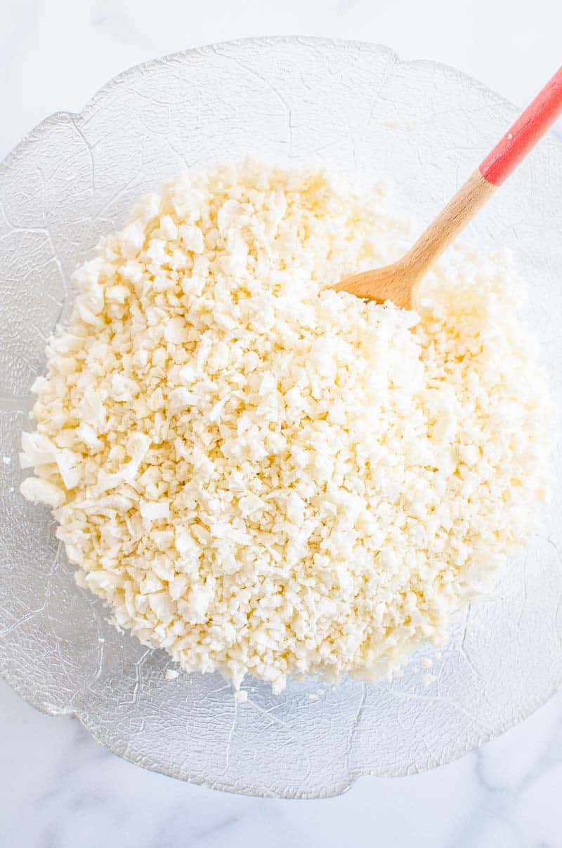 Cauliflower Rice in a glass bowl with a wooden spoon