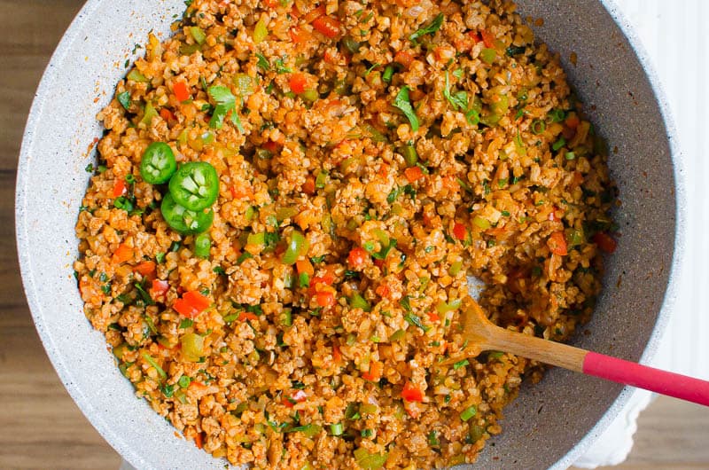 Mexican Cauliflower Rice in a skillet with a spoon